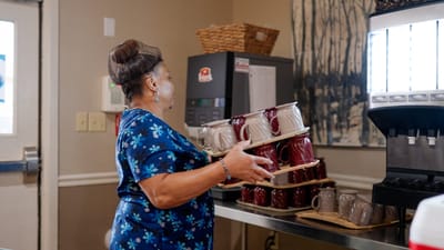 Staff member stacking mugs in an interior kitchen