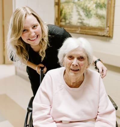 Caregiver and resident smiling in a hallway