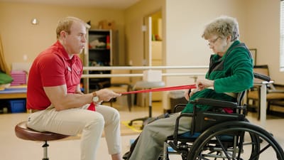 Therapist assisting a senior with resistance band exercise
