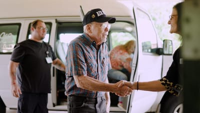 A senior man shaking hands with a staff member.