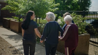 Staff assisting residents in an outdoor garden area