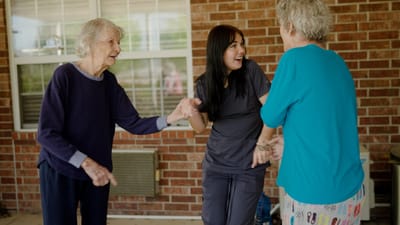 Residents engaging with staff outdoors on a sunny day