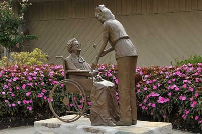 Bronze statue of a nurse assisting a senior woman