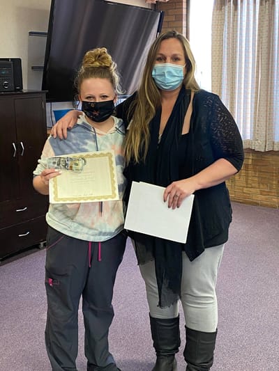 Two staff members posing with an award certificate