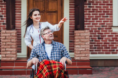 A caregiver pushing a resident in a wheelchair outside