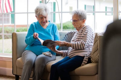 Two residents reading together in a common area