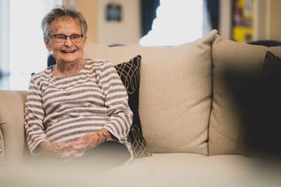 Resident smiling while sitting on a couch