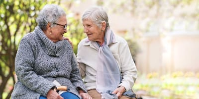 Two seniors sitting together in a garden