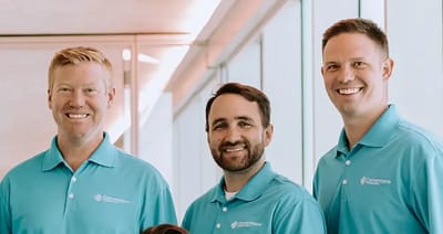 Three staff members smiling in blue polo shirts