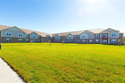 Exterior view of a senior living facility with green lawn