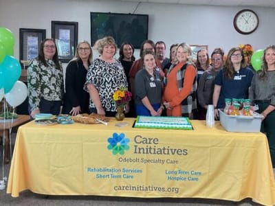 Staff and residents celebrating with a cake and decorations