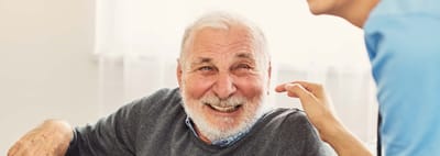 A senior man smiling during a conversation with staff