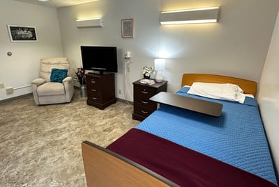A private resident room with a bed and chair