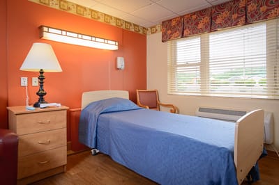 A cozy resident room with a bed and lamp