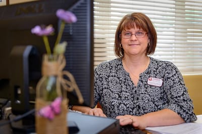 Staff member at a desk with flowers in the foreground