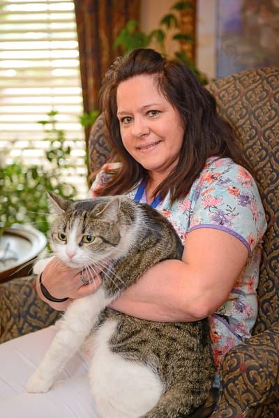 Staff member holding a cat in a cozy living room