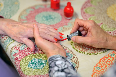 Staff painting resident's nails in a cozy setting