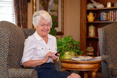 Senior resident using a smartphone in a cozy lounge