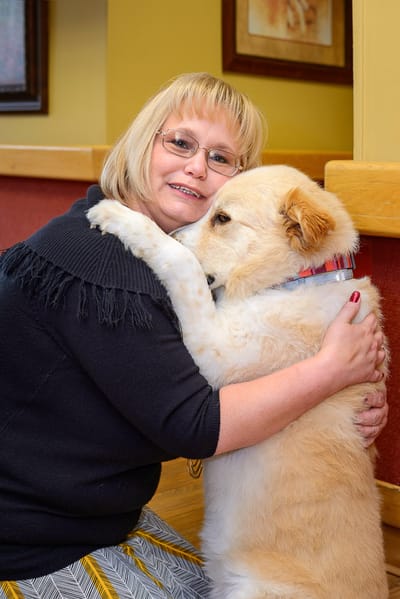 A resident hugging a therapy dog in a cozy interior