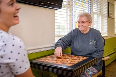 A resident enjoying a game of chess with staff member