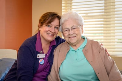 Staff member and resident smiling together in a room