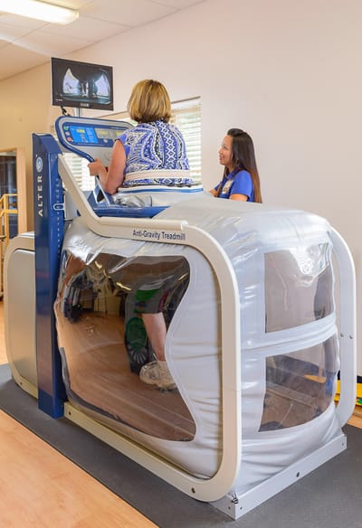 Residents using an anti-gravity treadmill with staff support