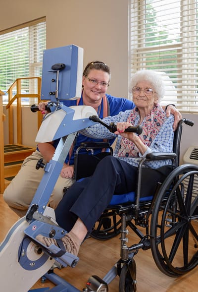 Staff assisting a resident with exercise equipment