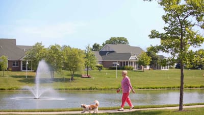 Resident walking a dog near a pond and fountain