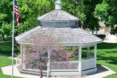 A gazebo surrounded by green grass and trees