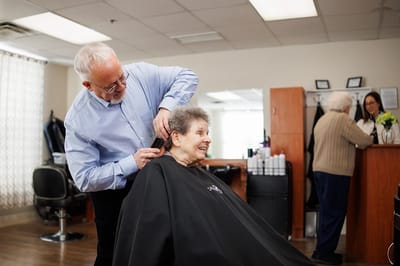 A stylist giving a haircut to a resident in a salon