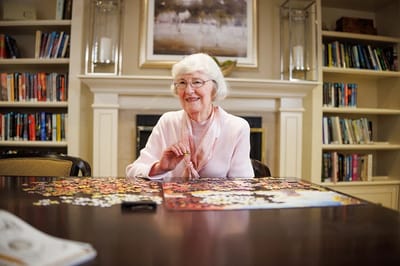 A smiling resident working on a jigsaw puzzle