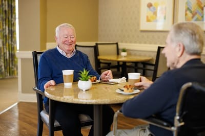 Residents enjoying coffee and muffins at a dining table