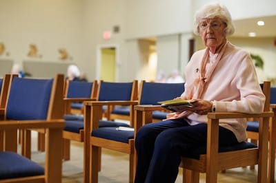 Senior resident sitting in a common area with empty chairs