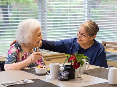 Resident enjoying a meal with staff in a dining area