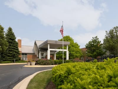 Front entrance of a senior living facility surrounded by greenery