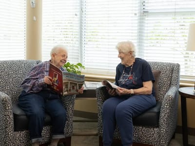 Two residents reading magazines in a cozy lounge