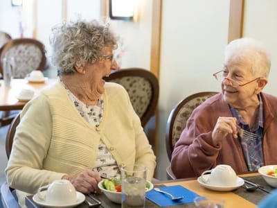 Two smiling residents enjoying a meal together