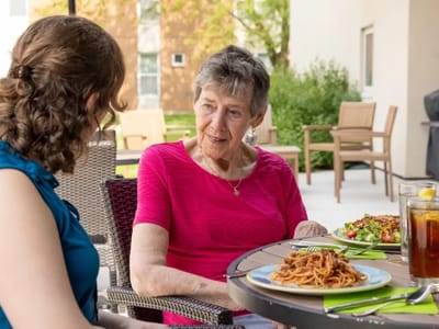 Residents enjoying a meal outdoors at a dining table