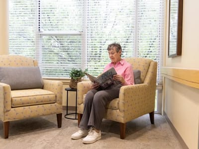 Elderly woman reading a magazine in a cozy chair
