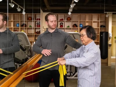 A staff member assisting a resident with resistance bands