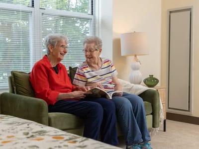 Two residents enjoying reading together in a cozy lounge
