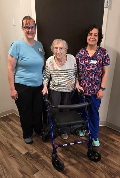 Two staff members with a resident in a facility hallway