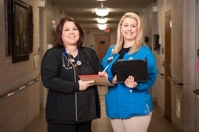 Two staff members in a well-lit hallway