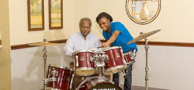 Resident and staff member playing drums together