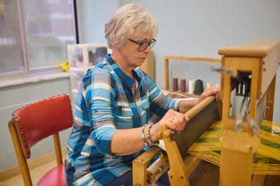 Resident engaged in weaving activity in a craft room