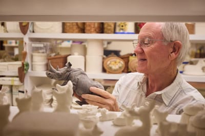A senior man showcasing a handcrafted rhino sculpture