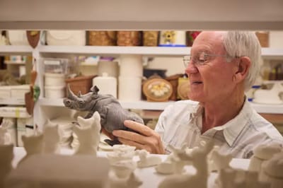 A senior man admiring a ceramic rhino sculpture