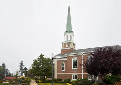 Exterior view of a facility with a steeple and landscaping