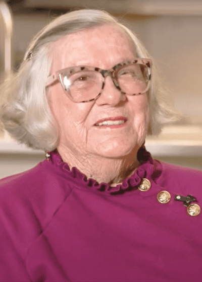 A smiling elderly woman with glasses in a living area