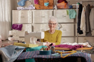 A resident sewing in a vibrant activity room
